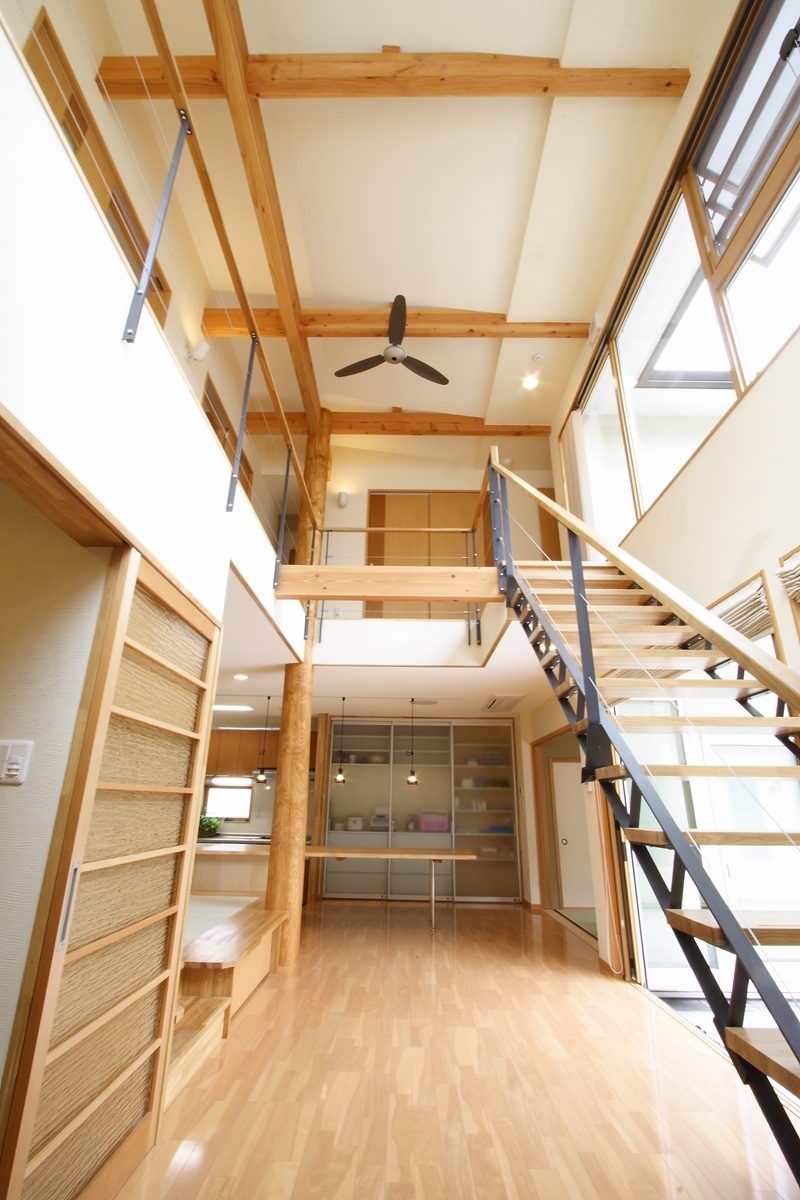 木の梁を活かした吹き抜けとオープン階段で上下階がつながる2階建て注文住宅の室内
