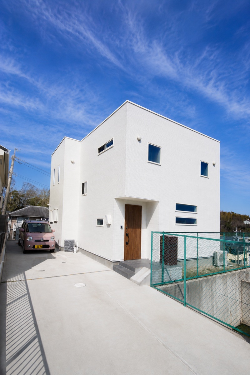 高低差のある旗竿敷地に建つ白い外観
